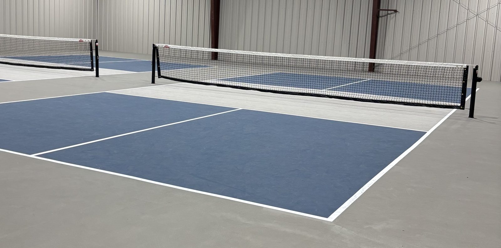 Indoor pickleball courts with painted lines and nets.